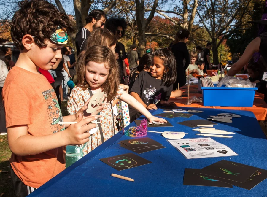 Children make scratch-art crafts at a table at Halloween Fest in Fort Greene Park