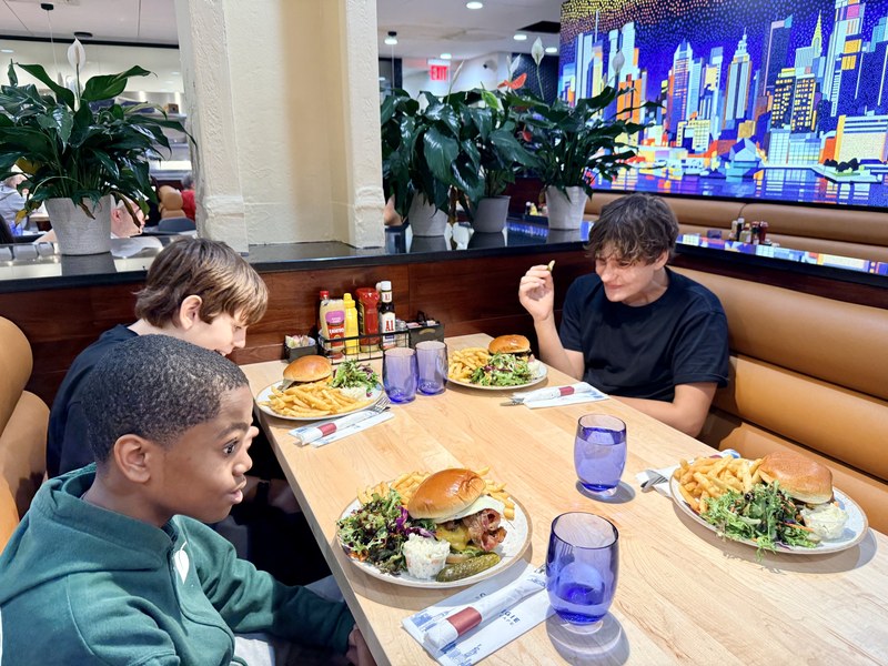 Three kids with burgers, fries and salads in a booth at Carnegie Diner & Cafe inside DeKalb Market Hall