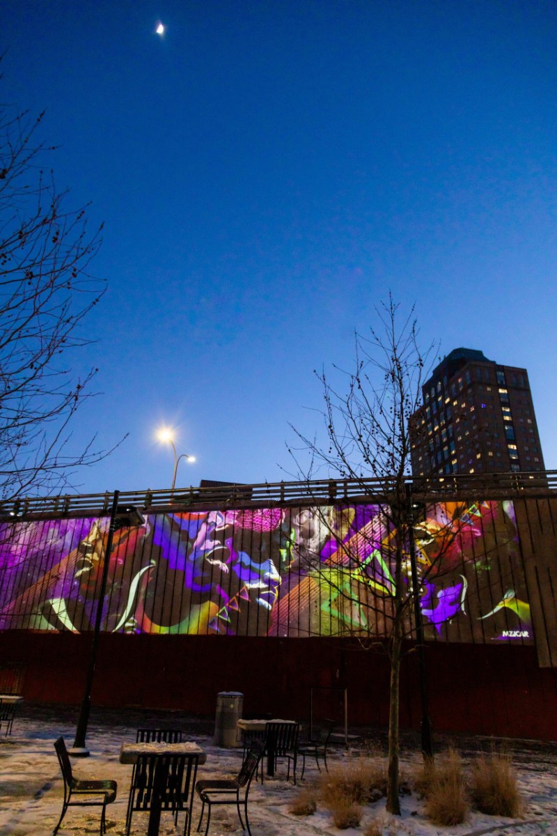 Video art projected onto a wall in Dumbo at dusk
