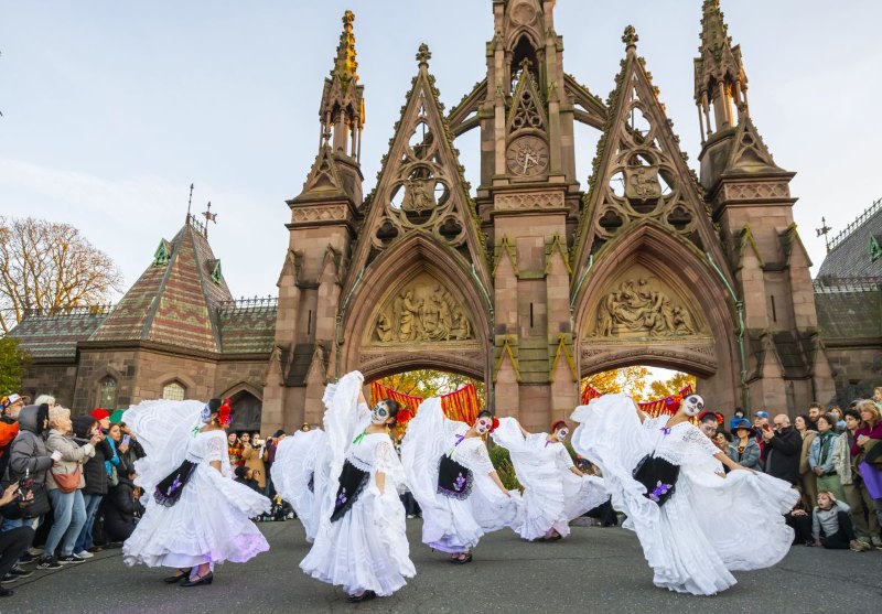 Dancers in white dresses perform in front of the Gothic gates at Green-Wood Cemetery during the Day of the Dead Family Celebration