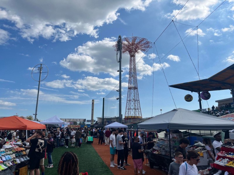 Crowds browsing sneaker vendor tents on the field at Maimonides Park with the Parachute Jump behind