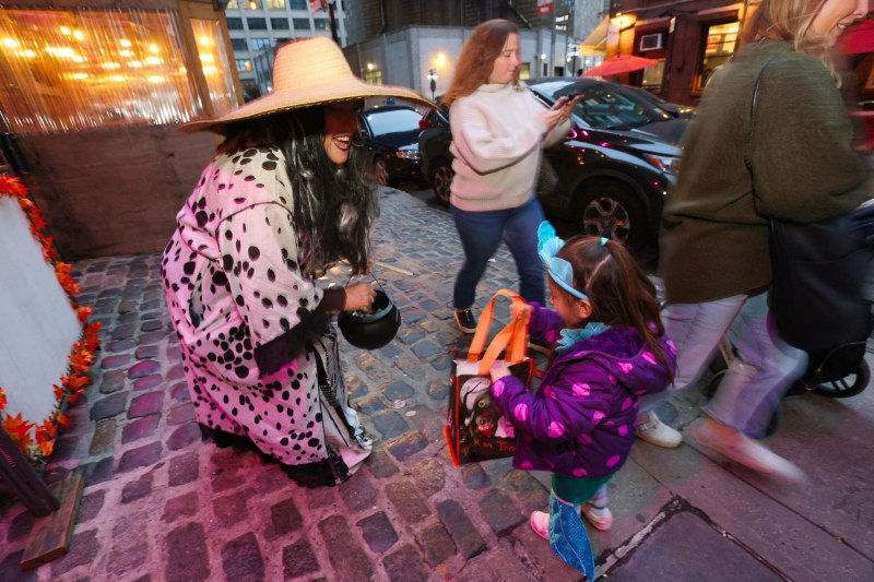 Trick-or-treaters in costume on a cobblestone street in DUMBO