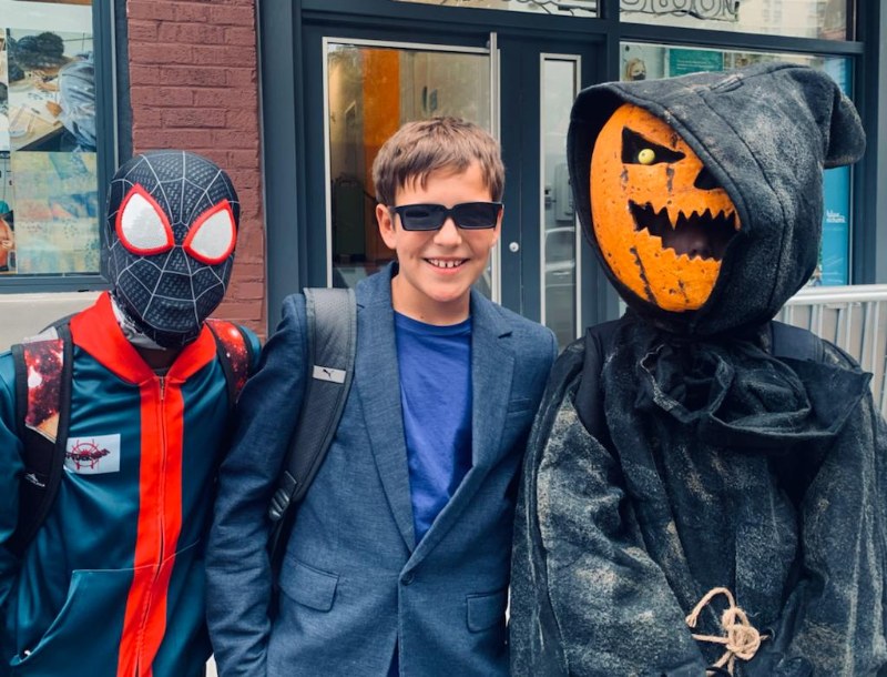 Three kids in Halloween costumes on a Brooklyn sidewalk