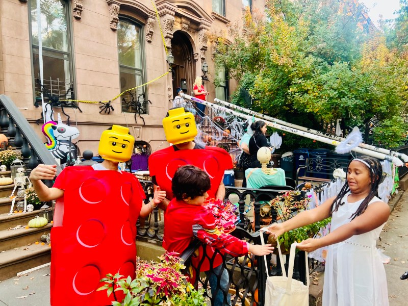 Kids in costume trick-or-treating at a decorated Park Slope brownstone stoop