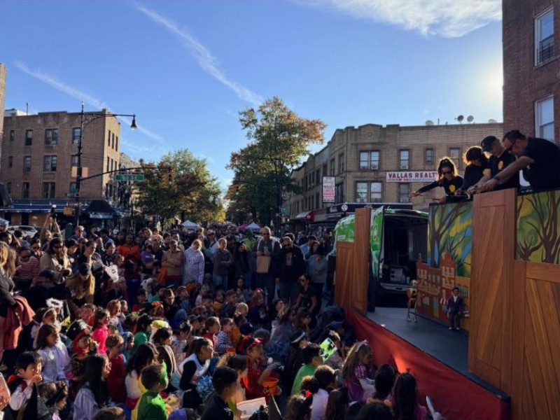 A crowd of children in costume watching the PuppetMobile show at Halloween Fest on Fifth Avenue in Bay Ridge