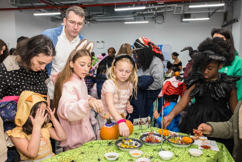 Children in costumes decorating pumpkins at a Brooklyn Bridge Parents fall event